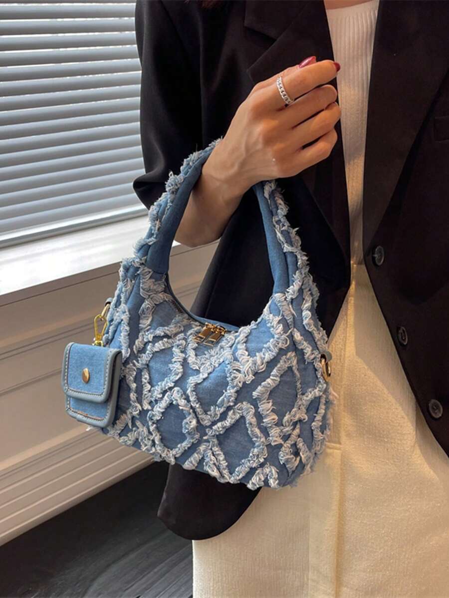 sac bleu brodee effilochee en jeans tenu par la main droite femme elegante