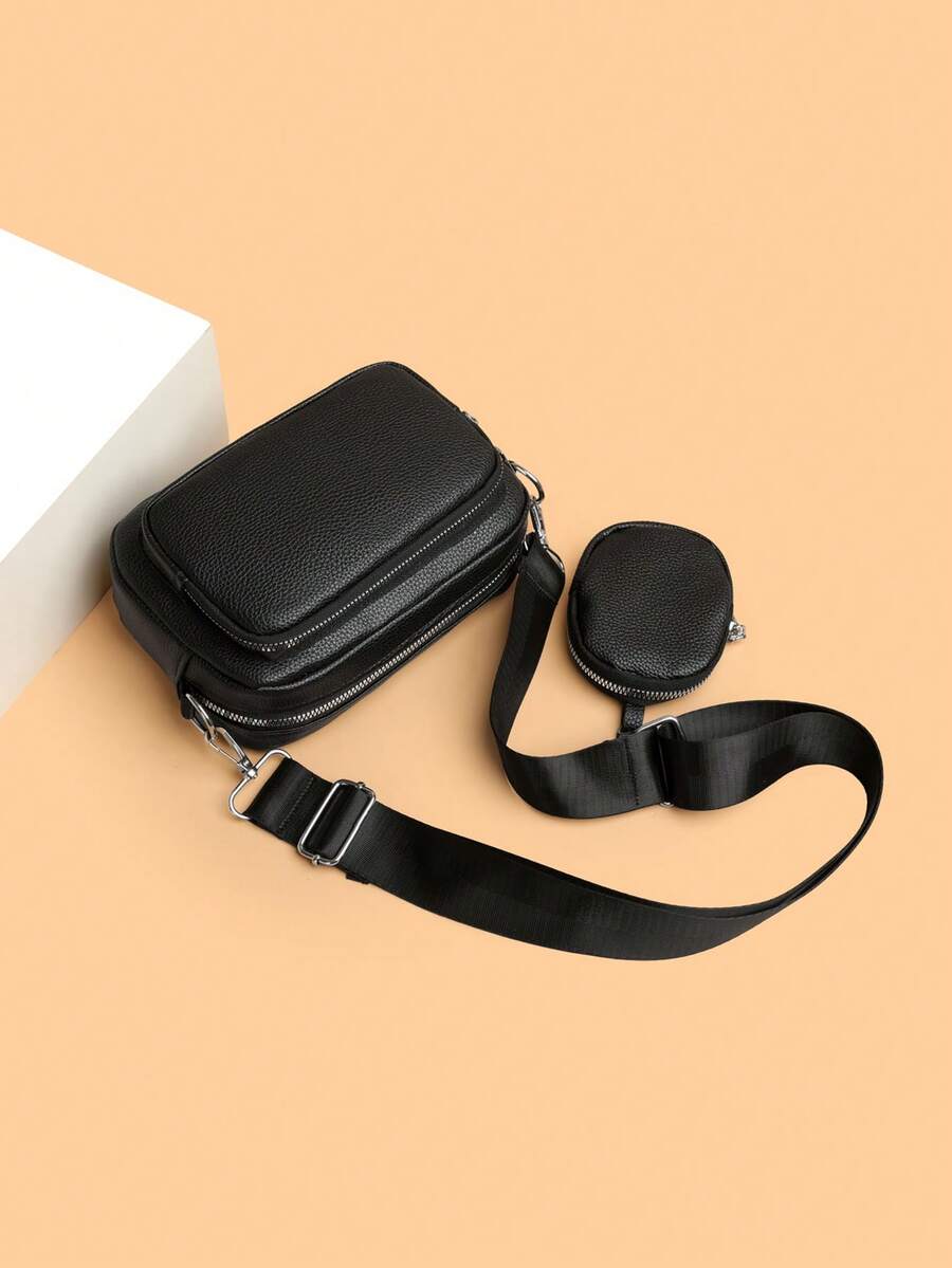 sacoche noir cuir sobre uni avec mini sacoche accrochee a la sangle pose sur le sol detail et accessoire