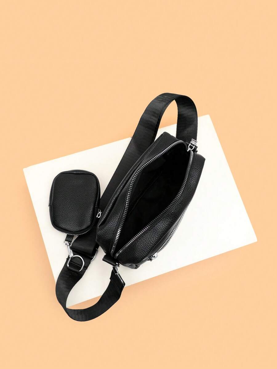 sacoche noir uni posee sur sol avec mini sacoche sur sangle ouverture fermeture eclair contenance